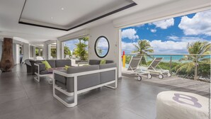 A modern living room with a grey sofa, a round mirror, and a view of the ocean. - At the entrance to Saint François, facing the waves with a panoramic sea view (ST FRANCOIS)