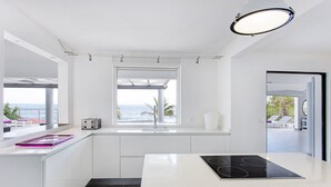 A modern kitchen with a view of the ocean, white cabinetry, and a built-in stove. - At the entrance to Saint François, facing the waves with a panoramic sea view (ST FRANCOIS)