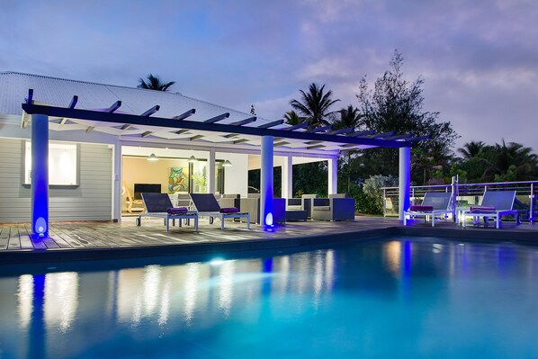 A poolside area with lounge chairs and a covered seating area.