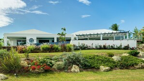 A modern house with a covered patio, surrounded by a well-maintained garden with various plants and flowers. - At the entrance to Saint François, facing the waves with a panoramic sea view (ST FRANCOIS)