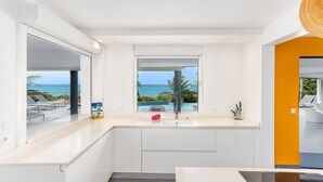A modern kitchen with a large window overlooking a pool and ocean view. - At the entrance to Saint François, facing the waves with a panoramic sea view (ST FRANCOIS)