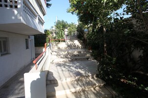 A staircase leading up to a building with a white exterior and a red handrail.