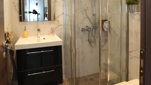 A modern bathroom with a glass-enclosed shower, a white sink, and a mirror above the vanity. - Edem Beach Apartment Mountain View (Palaio Faliro)