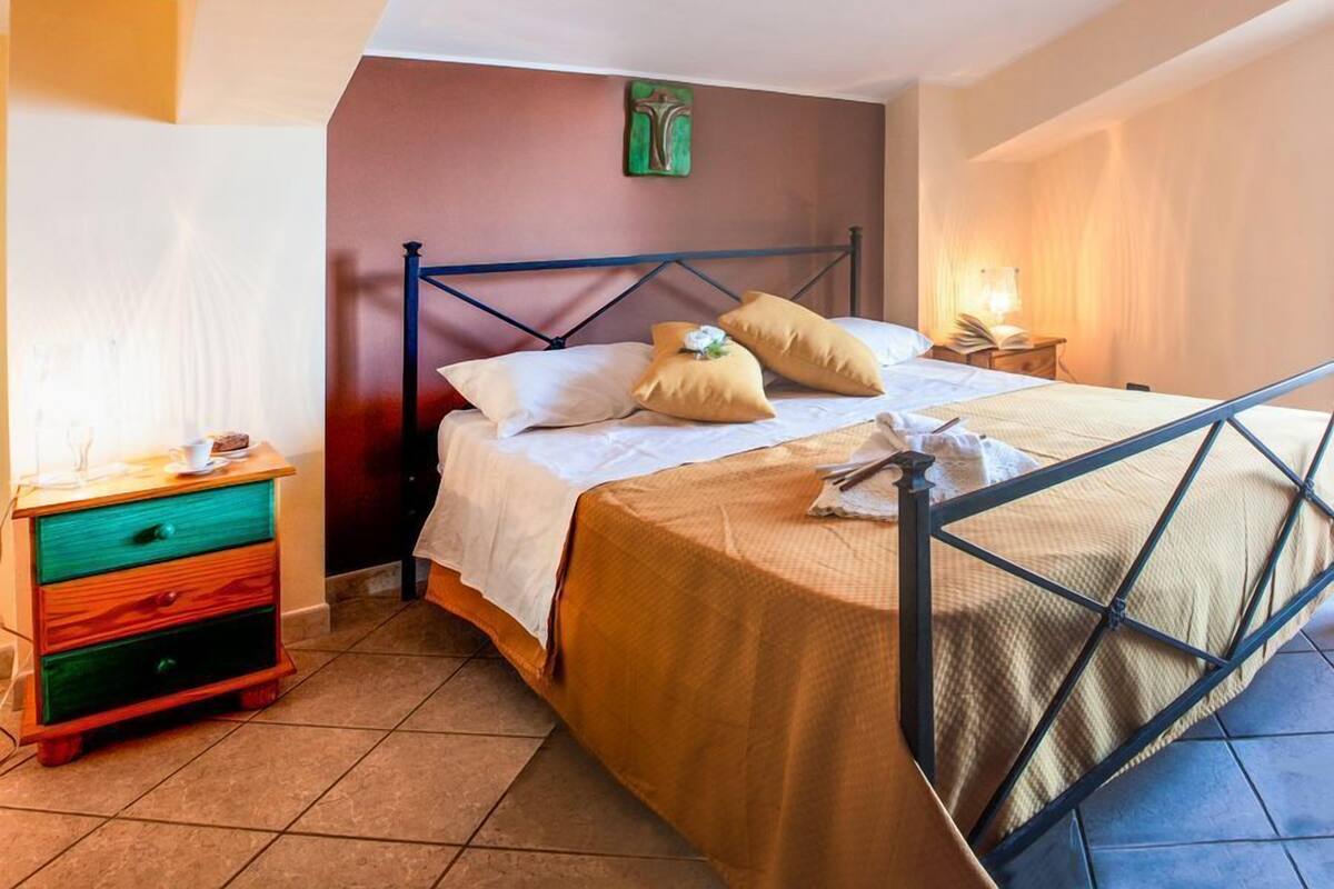 A bedroom with a bed, a nightstand, a dresser, and a wall-mounted light.