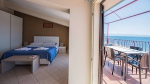 A bedroom with a bed, bedside tables, and a balcony with a table and chairs. - La Sirena Bed & Breakfast (Santa Teresa di Riva)