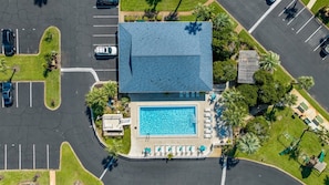 Vista aérea de um hotel com piscina, estacionamento e áreas verdes ao redor.
