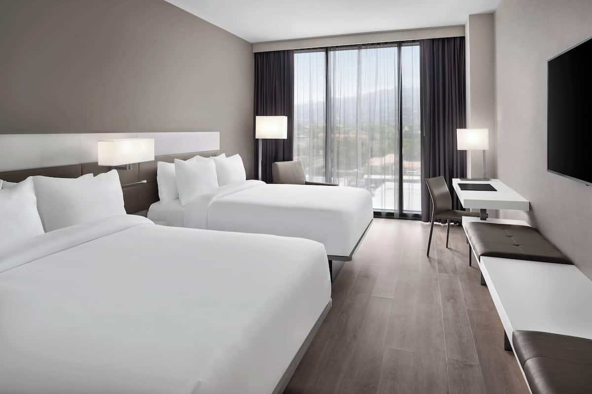 Une chambre d’hôtel avec deux lits, un bureau et une télévision.