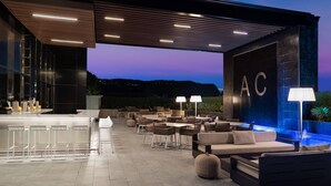 Un espace de détente extérieur moderne, doté d’un bar, de tables et d’une piscine.