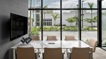Una sala de conferencias moderna con una amplia mesa de vidrio, cuatro sillas y un televisor montado.