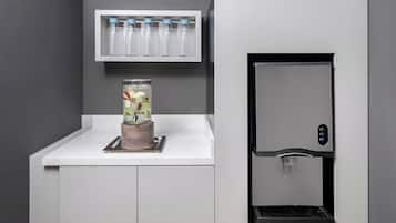 A modern kitchen with a built-in water dispenser and a glass container with fruits on the counter.