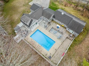 Ein zweistöckiges Haus mit einem großen rechteckigen Pool, einer überdachten Terrasse und einem umzäunten Garten.