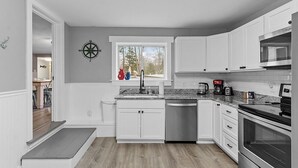 A modern kitchen with white cabinetry, a built-in dishwasher, a stove, and a microwave.