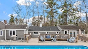 A residential setting with a swimming pool, deck chairs, and a barbecue area.