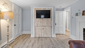 A hallway with a wooden wall panel, a flat-screen TV, and a fireplace.