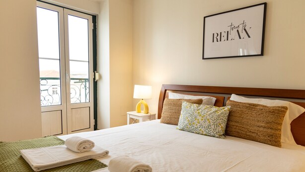 Une chambre d’hôtel avec un lit, un panneau encadré accroché au mur, une fenêtre et une porte.