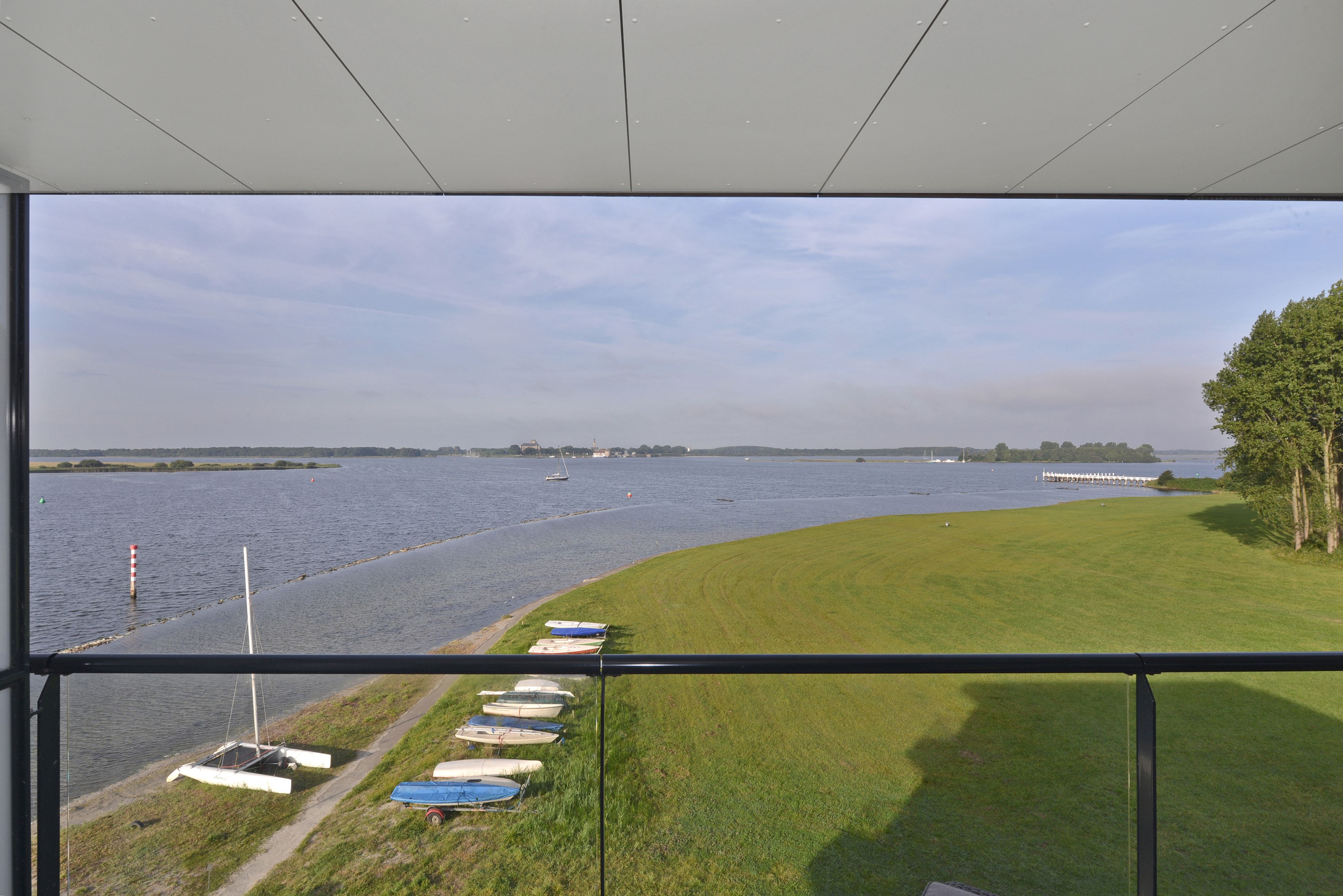 A view from a window overlooking a calm body of water with several boats docked along the shore.