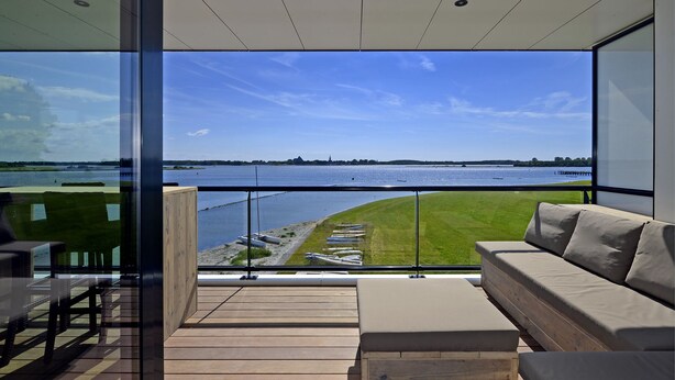 Un balcon moderne offrant une vue sur une rivière et un paysage lointain.
