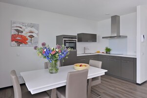 A modern kitchen with a built-in oven, a stainless steel range hood, and a white countertop.