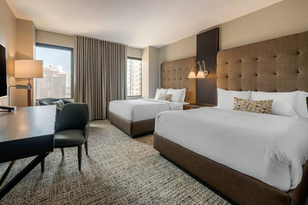 Ein Hotelzimmer mit zwei Betten, einem Schreibtisch und einem Stuhl.