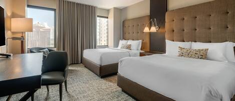 A hotel room with two beds, a desk, and a chair.