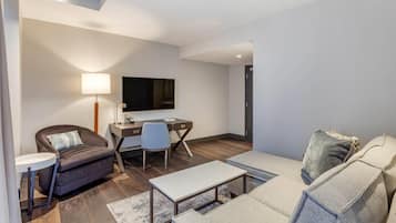 Uma sala de estar moderna com sofá, poltrona, escrivaninha e televisão.