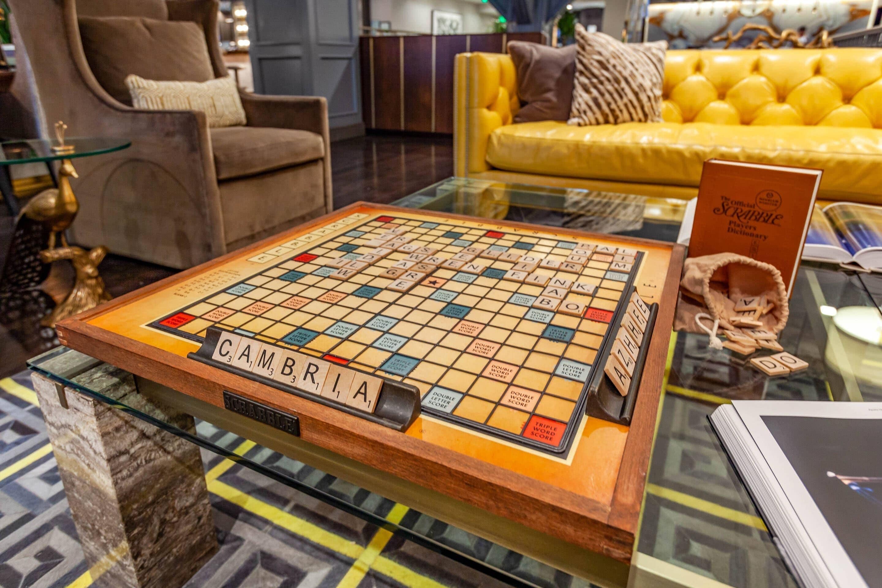 A Scrabble board game on a glass table with a sign reading "Cambria" in the center.