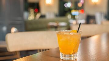 A glass of orange beverage on a wooden table in a restaurant setting.