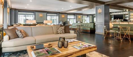 A spacious living area with a sofa, coffee table, and chairs. There is a bar area with stools and a television.