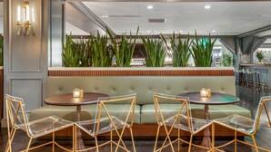 Een restaurant met een groen gestoffeerde zithoek, transparante glazen stoelen en een houten tafel.