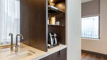 Una cocina moderna con cafetera integrada, un estante con libros y una ventana con vistas a la ciudad.