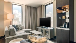 Een moderne hotelkamer met een bank, fauteuil en televisie.