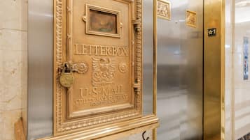 Deur van een lift met gouden lijst, met de tekst: Letterbox U.S. Mail Cutter Mail Chute Co. Rochester, NY.