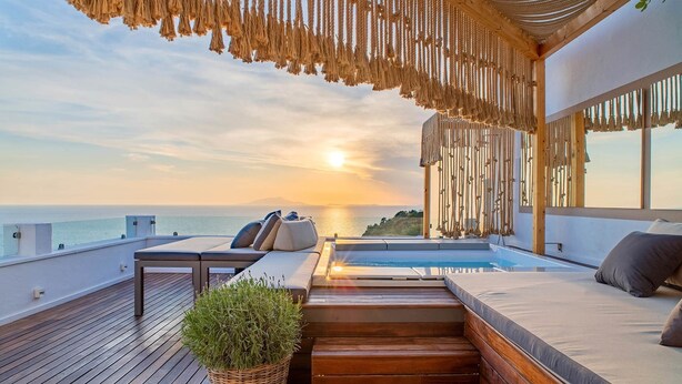 A rooftop terrace with a pool, wooden deck, and seating area overlooking the sea during sunset. - Casa Mariavittoria (Massa Lubrense)