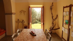 A dining area with a wooden table, chairs, and a view of the outdoors through an open door.