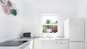 A modern kitchen with white cabinetry, a built-in microwave, a dishwasher, and a refrigerator.