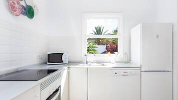 Een moderne keuken met witte kasten, een ingebouwde magnetron, een vaatwasser en een koelkast.