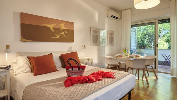 A hotel room with a bed, a desk, and a view of the outdoors. - Sunny apartment view on St. Peter's secure parking (Roma)