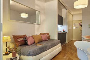 Un dormitorio moderno con una cama, una mesita de noche con una lámpara y un espejo grande.