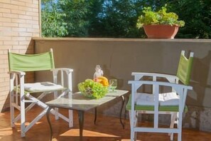 Ein Balkon mit zwei weißen Stühlen, einem kleinen Tisch und einem Blumentopf.