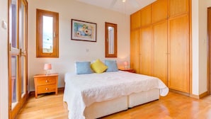 Een slaapkamer met een groot bed, een houten garderobe en een schilderij aan de muur.