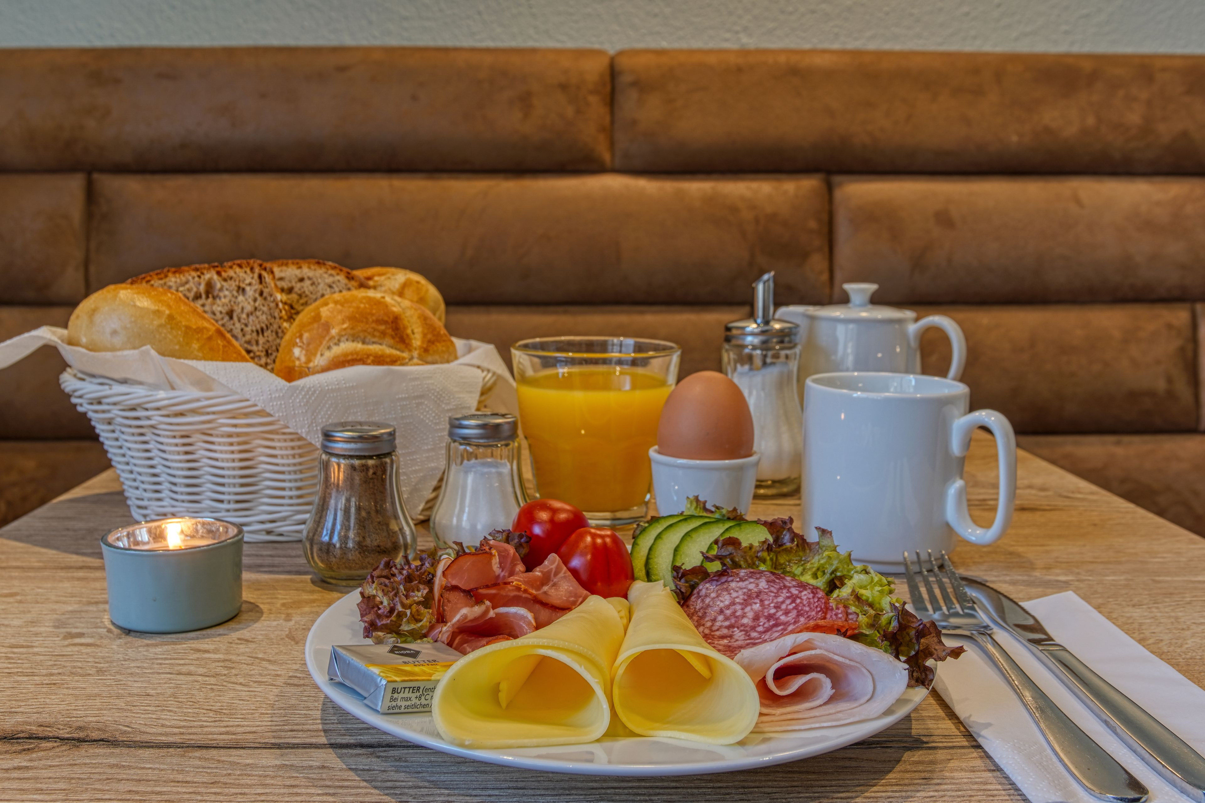 A breakfast setting with bread, eggs, cheese, ham, tomatoes, and a drink on a table.