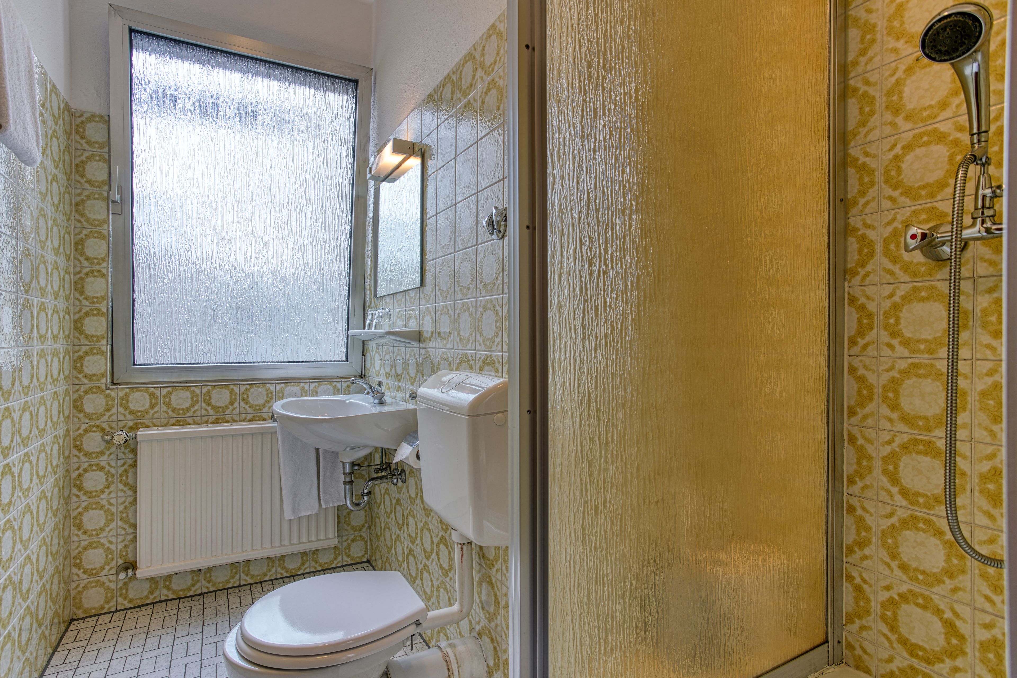 A bathroom with a toilet, sink, and shower.