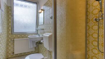 A bathroom with a toilet, sink, and shower.