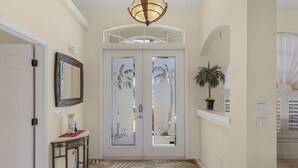A hallway with a double door, a mirror, a console table, and a patterned carpet. - Close your eyes and imagine - SW Cape waterfront home with fully Inclusive rates (Cape Coral)