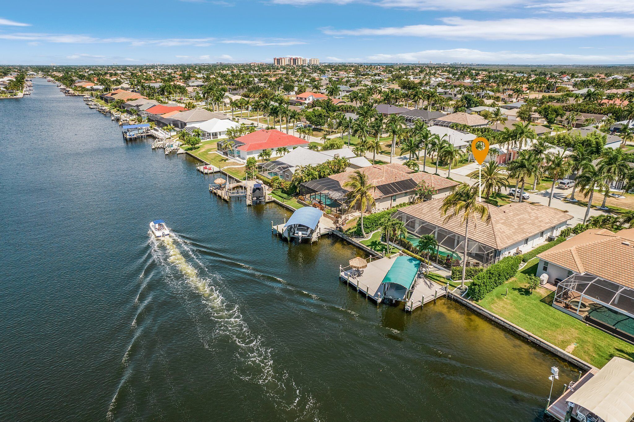 Vista aérea de una zona residencial frente al agua, con casas, muelles y un barco.