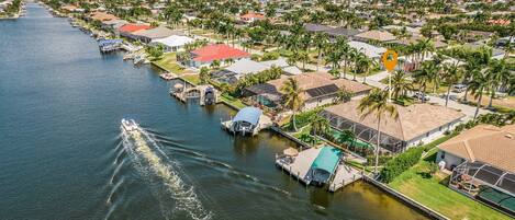 Vista aérea de una zona residencial frente al agua, con casas, muelles y un barco.