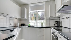 Una cocina moderna con armarios blancos, encimera negra y ventana que aporta luz natural.