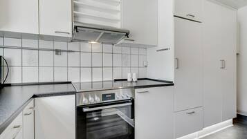 A modern kitchen with white cabinets, a stainless steel oven, and a black countertop.