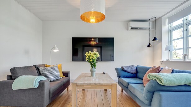 Una sala de estar moderna con dos sofás, una mesa de centro, un televisor y una lámpara colgante.
