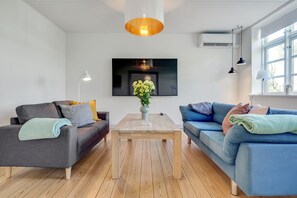 A modern living room with two sofas, a coffee table, a TV, and a hanging light fixture. - Apartment 2 bedroom with lake view (Krusaa)